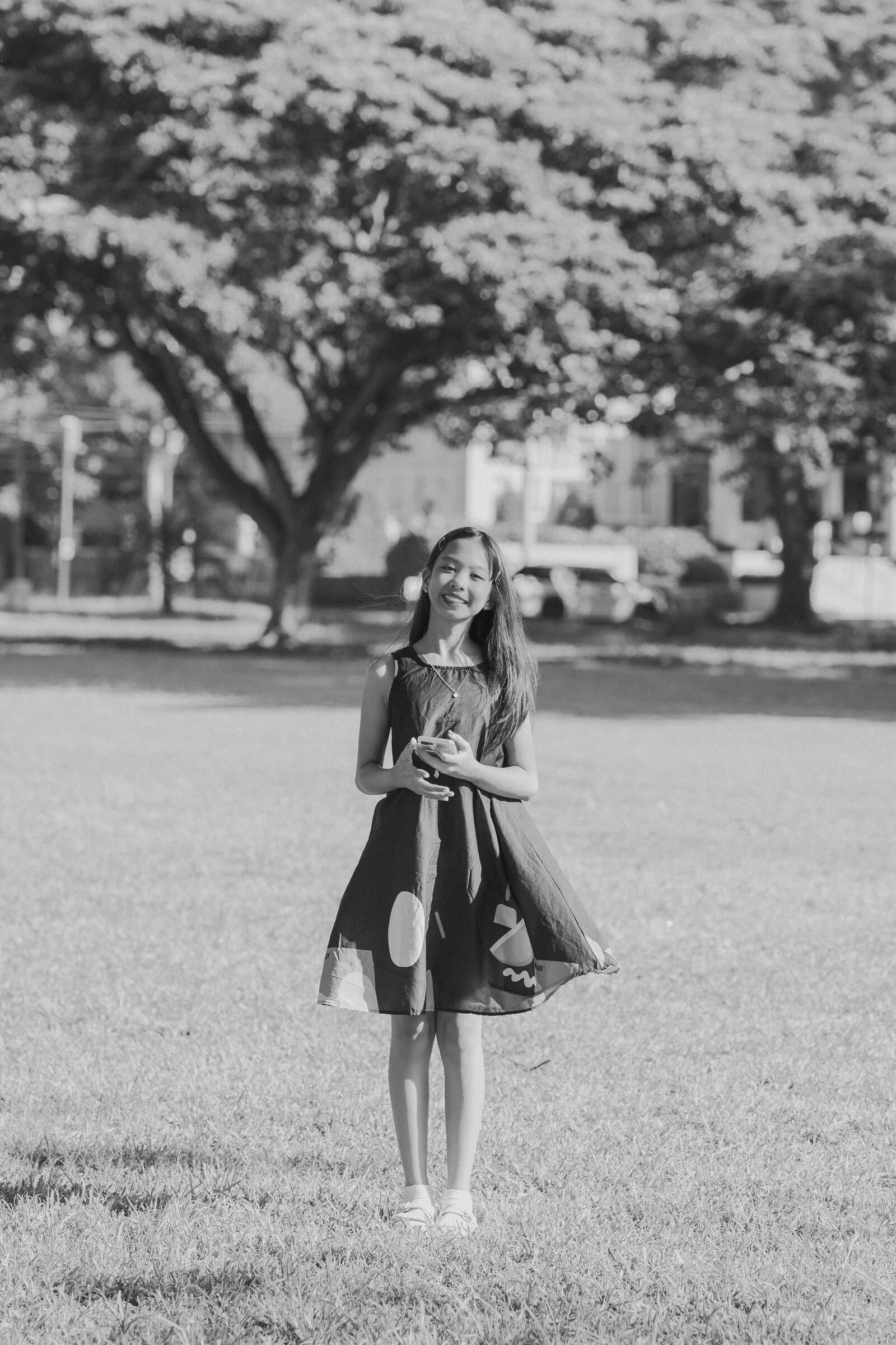 Portrait in a flowing dress under park trees, black and white